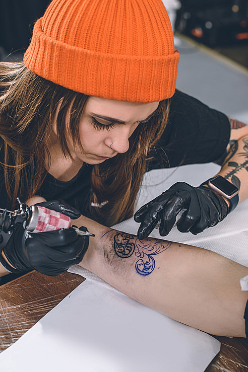 Woman tattoo artist during tattooing process