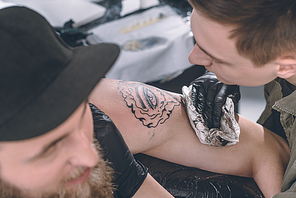 Master in gloves working on shoulder tattoo in studio