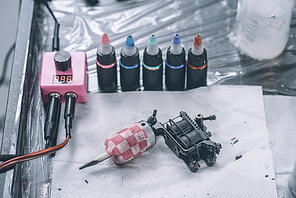 Tattoo artist workplace with machine and bottles with colorful tattoo ink