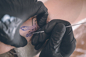 Close-up view of tattoo artist in gloves working on arm piece