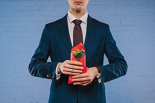 cropped shot of young businessman in suit holding doner covered in red paper