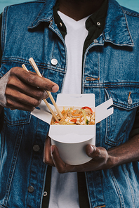 cropped shot of african american man holding box of chinese takeout noodles