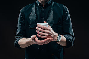 Close-up view of coffee cup in male hands isolated on black