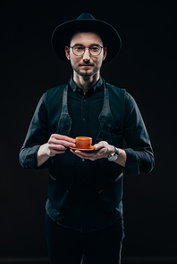 Stylish man holding cup with coffee isolated on black
