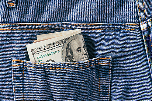 close up view of dollars banknotes in jeans pocket