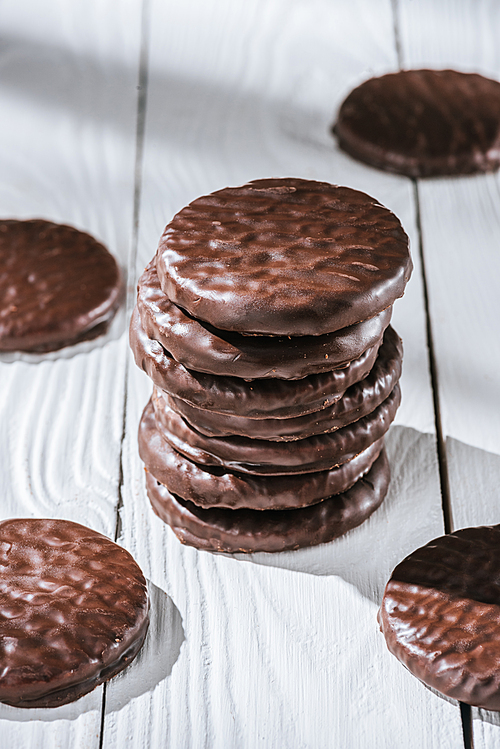 close-up shot of stack of delicious glazed chocolate cookies on white wooden table