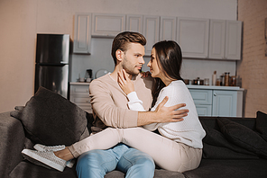 romantic young couple cuddling on couch at home