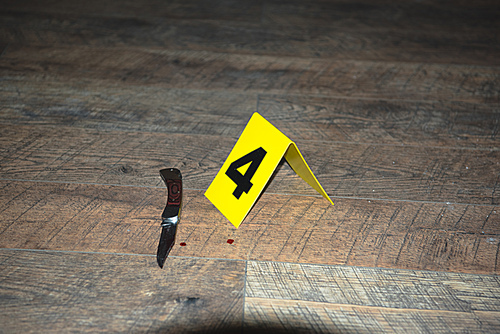 knife at fresh crime scene with evidence marker on wooden floor