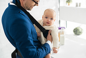 infant daughter in babycarrier with father in suit