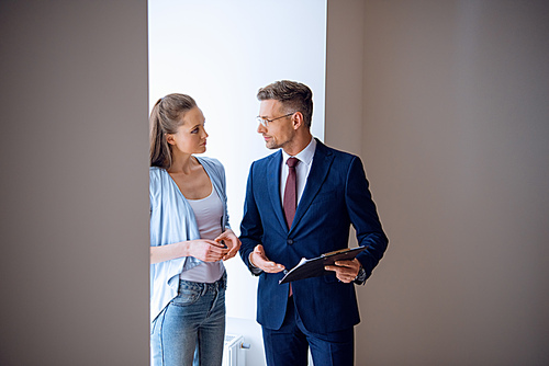 handsome broker looking at beautiful woman while standing in room