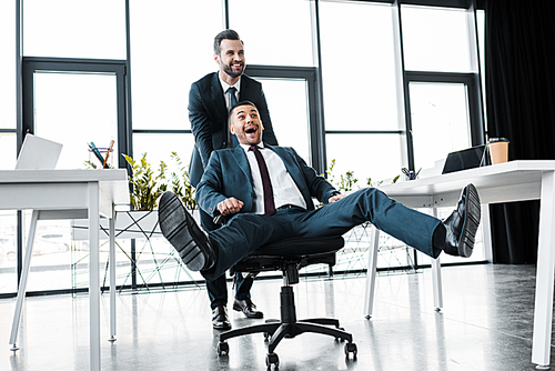 유토이미지 | happy businessman pushing chair with cheerful coworker in ...