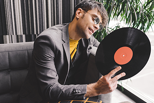cheerful young man in sunglasses looking at vinyl record