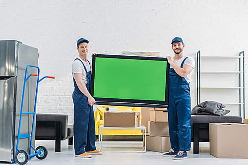 two movers in uniform  while transporting tv with green screen in apartment