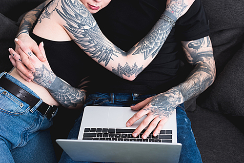 cropped image of tattooed couple using laptop
