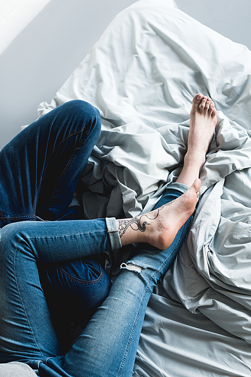 cropped image of tattooed couple lying on bed at home