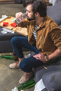 high angle view of loner drinking water and having hangover at living room