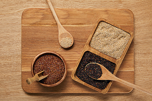 top view of white, black and red quinoa on wooden chopping board
