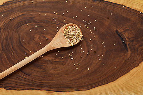 top view of white quinoa in wooden spoon on beige and brown table