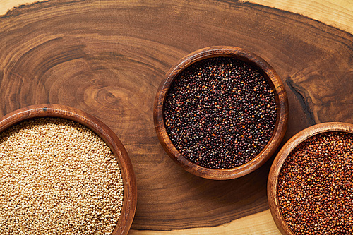 top view of white, black and red quinoa in wooden bowls