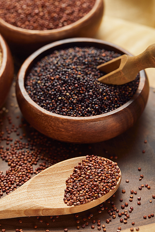 close up view of black and red quinoa in wooden bowl with spatula near spoon