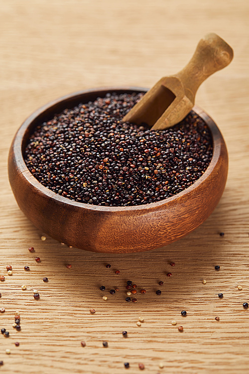 black quinoa seeds in wooden bowl with spatula