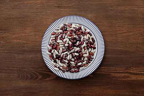 top view of striped plate with raw beans on wooden table