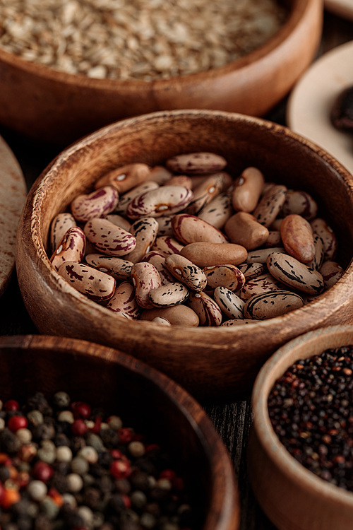 close up view of wooden bowls with beans, grains and peppercorns