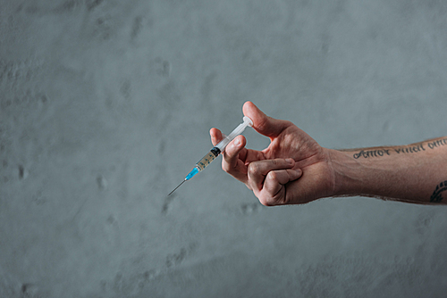 cropped shot of junkie holding heroin syringe