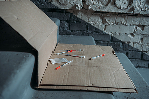 close-up shot of heroin syringes on cardboard and on stairs