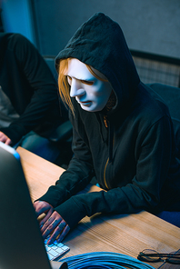 high angle view of hacker in mask working with computer to develop malware