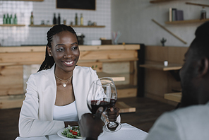 partial view of african american couple clinking glasses of wine in restaurant