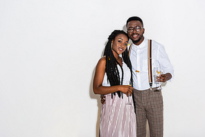 stylish young african american couple embracing and holding glasses of wine on white