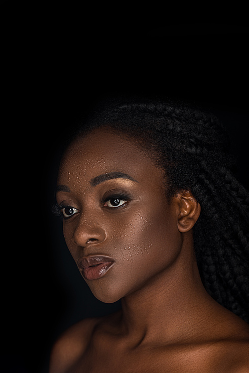 beautiful sensual young african american woman with water drops on face looking away isolated on black