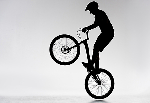 silhouette of trial biker performing bunny hop on white