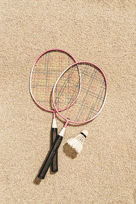 top view of arranged badminton rackets and shuttlecock on sand