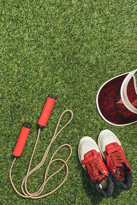 top view of arranged jump rope, cap and sneakers on green grass