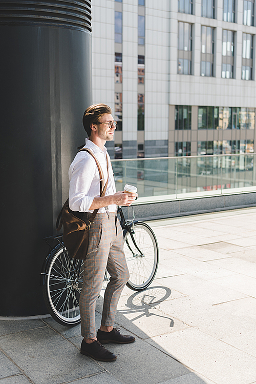 stylish young man with coffee to go and vintage bicycle on rooftop of business building