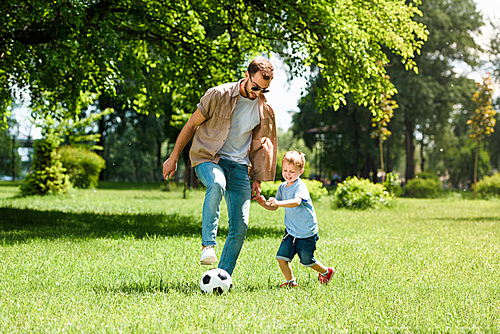 dad and son playing football at park