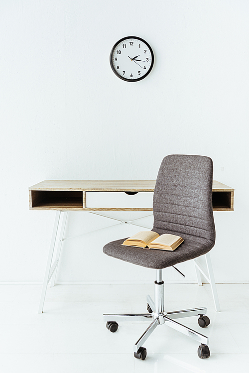 stylish office furniture with old book in front of white wall with clock