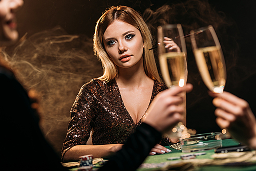 girls clinking with glasses of champagne at poker table in casino