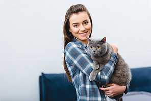 girl holding british shorthair cat and smiling at camera