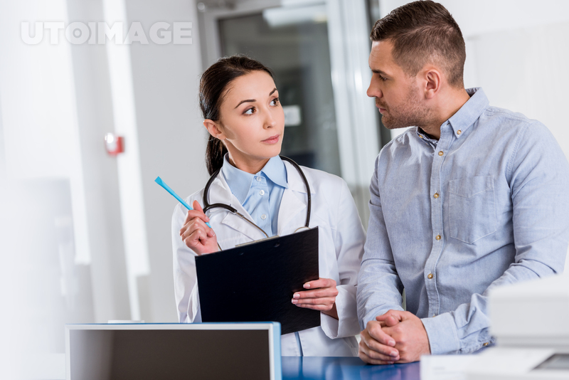 유토이미지 | Brunette doctor with clipboard talking to patient in clinic
