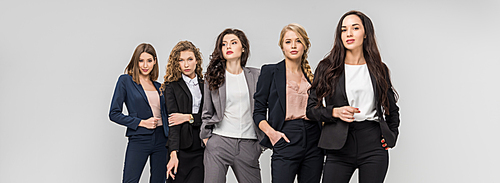 beautiful young women standing with hands in pockets isolated on grey