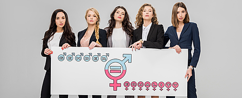 successful young women holding large sign with gender equality symbol isolated on grey