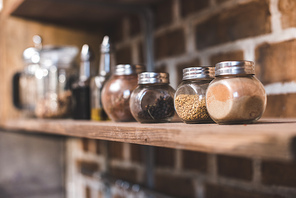 selective focus of arranged jars with various spices on kitchen shelf