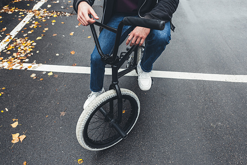 cropped shot of young man riding bmx bicycle on street