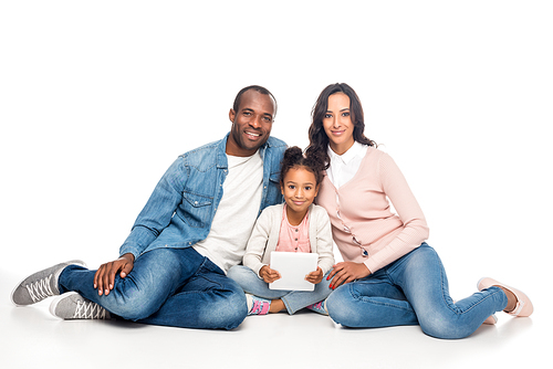 african american family with one child using digital tablet and smiling at camera isolated on white