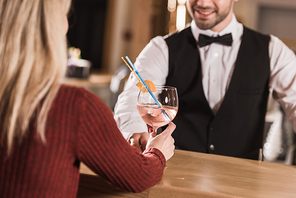Cropped image of Smiling bartender giving alcohol cocktail to female client