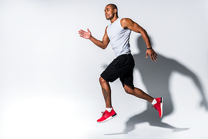 athletic young african american sportsman running on grey