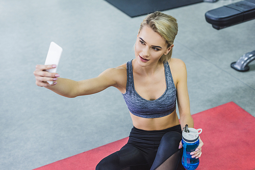 high angle view of young smiling woman taking selfie while training